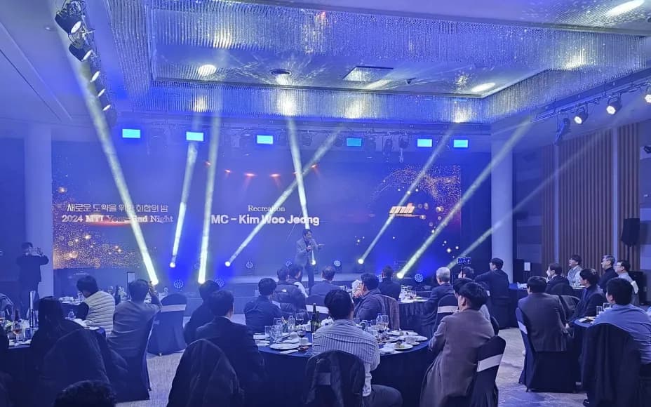 무빙라이트가 켜진 연회장 무대에서 사회자가 진행하는 기업 송년회
