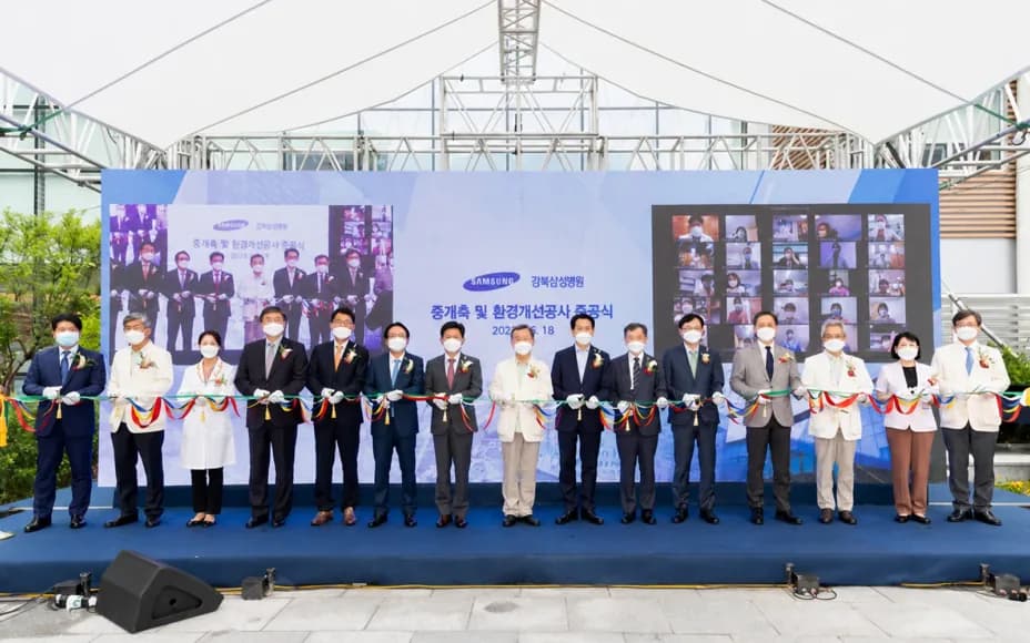 야외 준공식 무대에서 오색 테이프를 한 줄로 잡고 선 참석자들