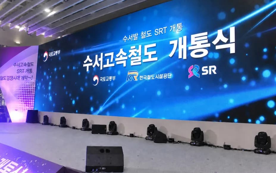 개통식 무대의 곡면 LED 백월과 바닥에 일렬로 놓인 무빙라이트