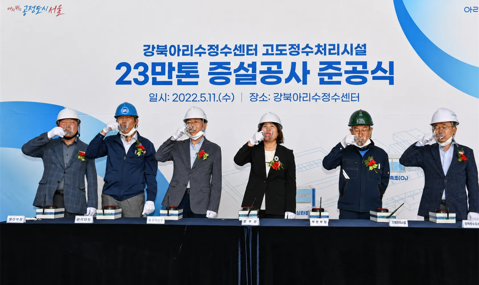 준공식 헤드테이블에서 안전모를 쓰고 시음 세리머니를 진행하는 모습