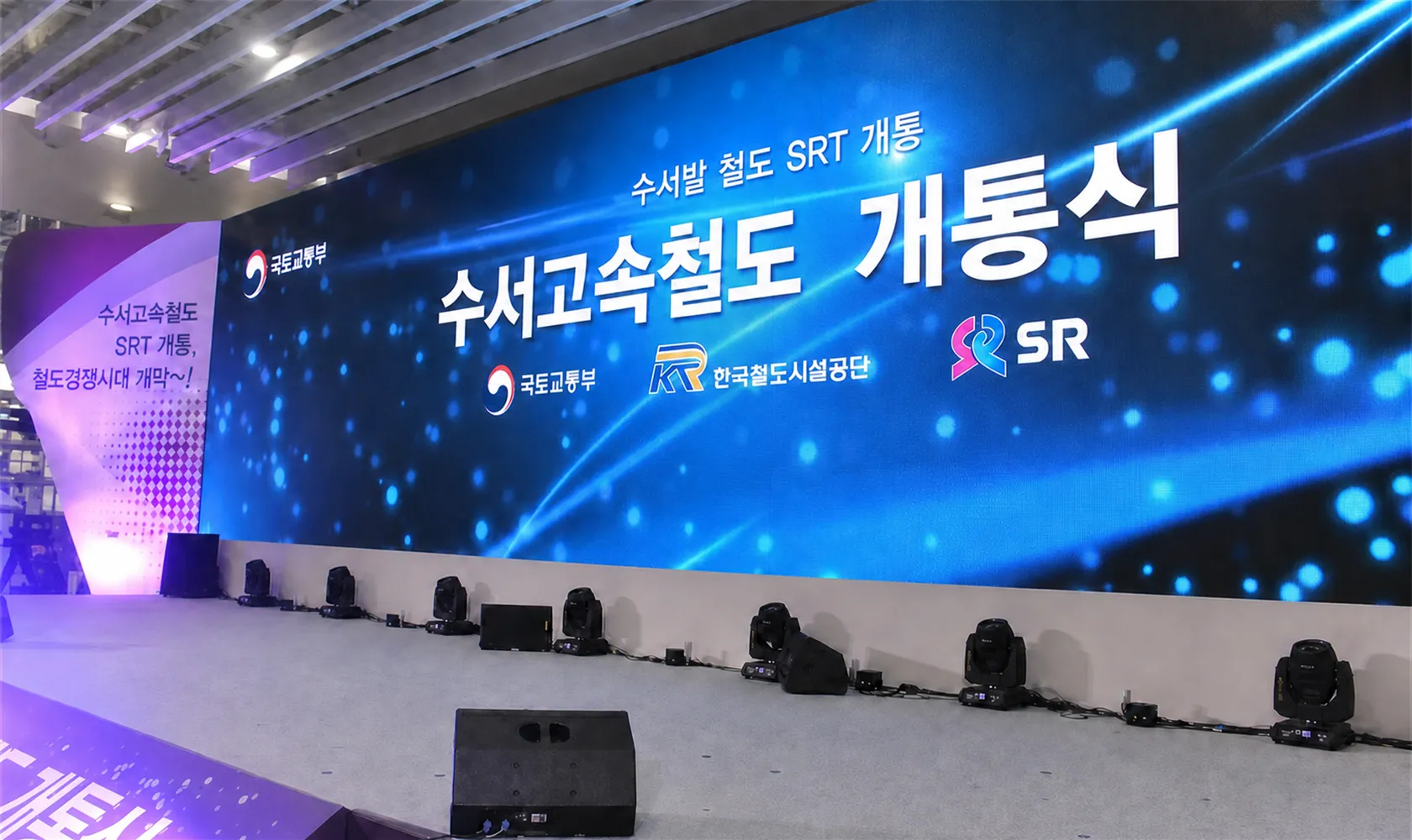 개통식 무대의 곡면 LED 백월과 바닥에 일렬로 놓인 무빙라이트