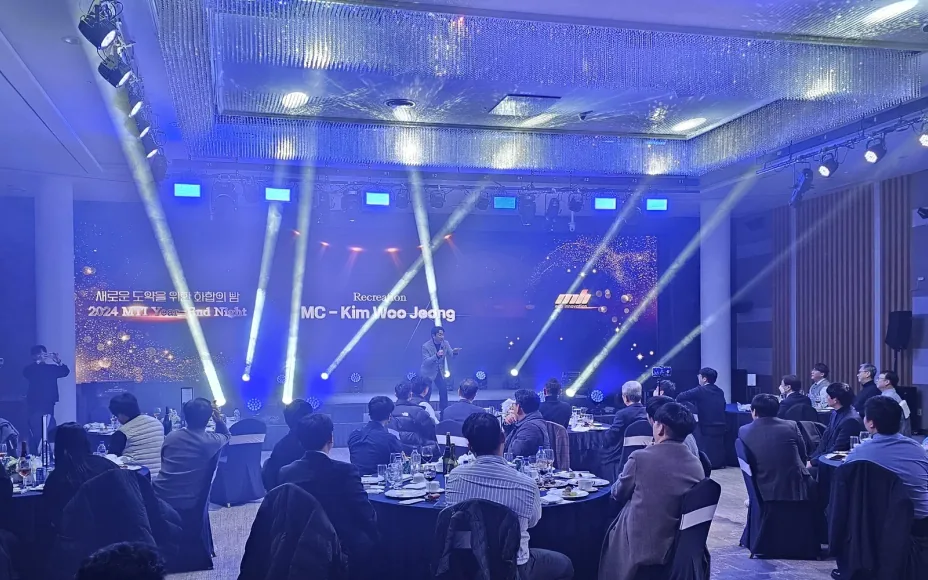 무빙라이트가 켜진 연회장 무대에서 사회자가 진행하는 기업 송년회