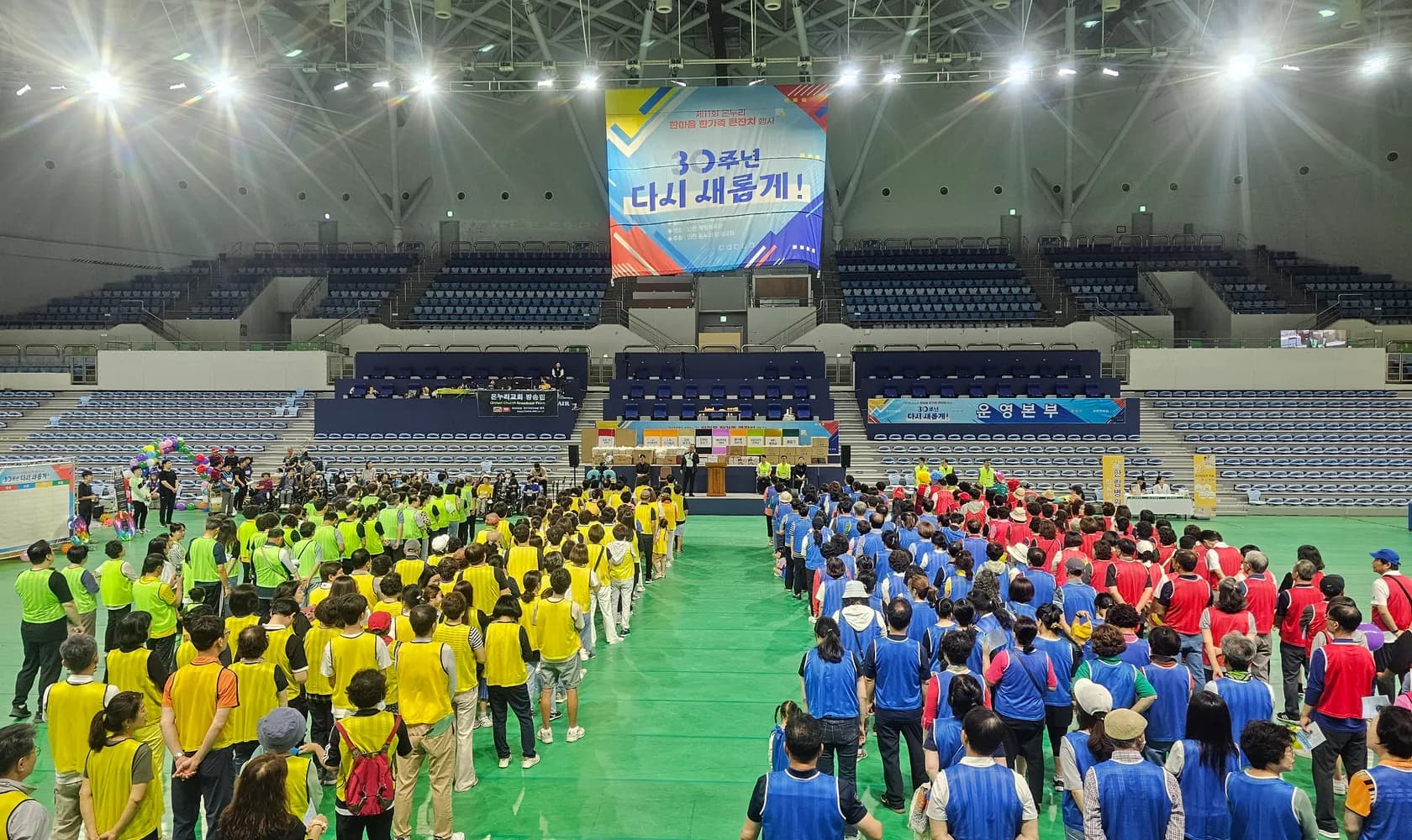 인천 계양체육관 코트에 네 색 조끼로 정렬한 체육대회 참가자와 천장 현수막