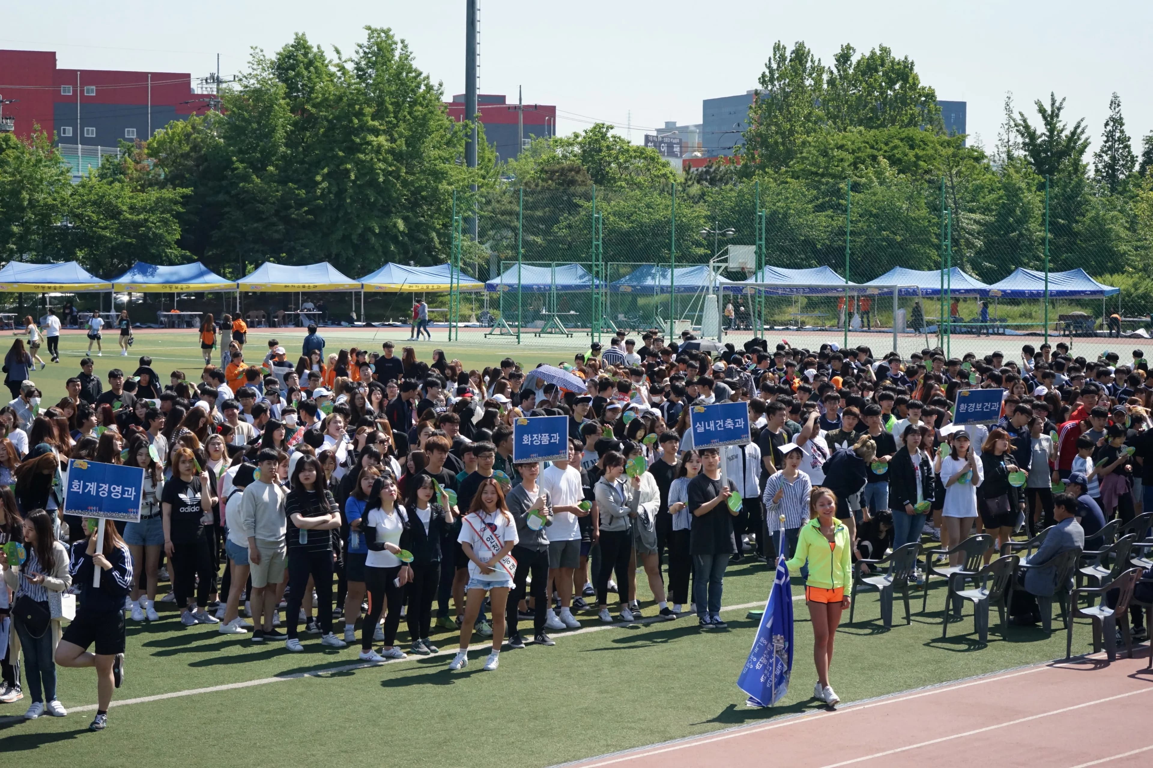 학과 피켓을 든 학생들이 운동장을 채우고 뒤로 팀 천막이 늘어선 체육대회
