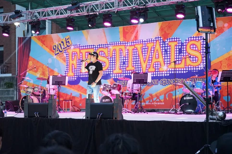 밤 FESTIVALS 배경 무대에서 밴드와 함께 공연하는 보컬